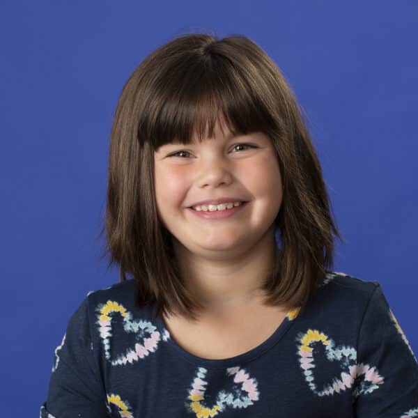 Early treatment jones family orthodontics Photo of young girl smiling infront of blue background