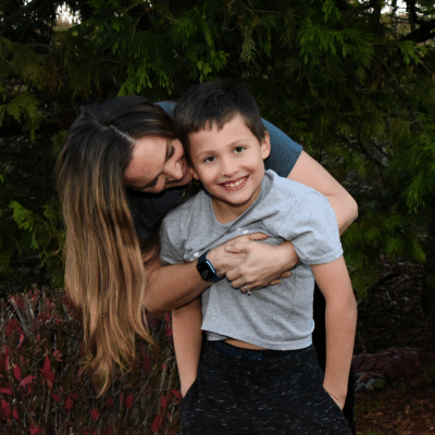 How to spot early signs of misaligned teeth 5 Woman playfully hugging a child outdoors, representing early signs of misaligned teeth