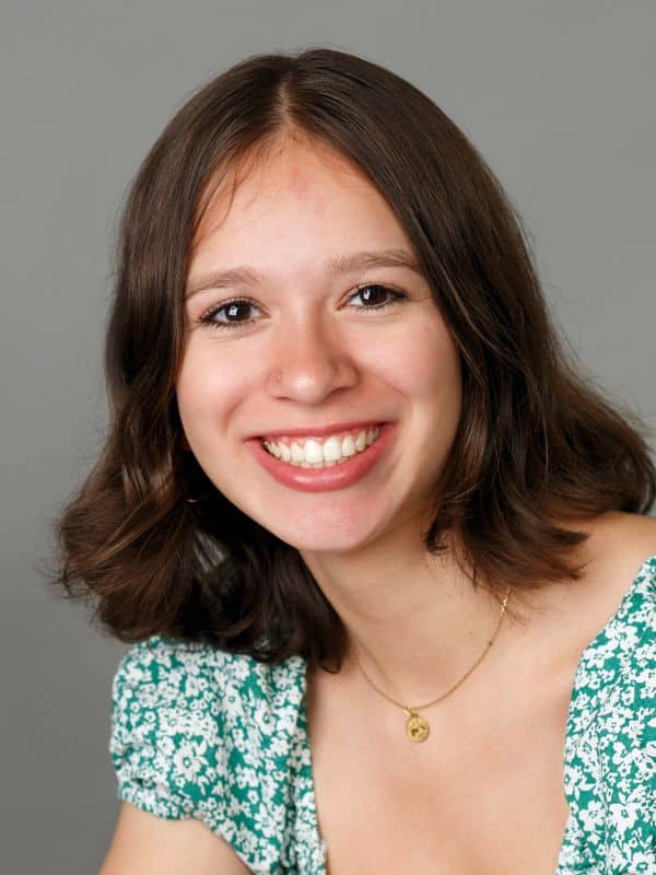 Beautiful smile after treatment Girl with short dark hair smiling in a green and white shirt after smile transformation