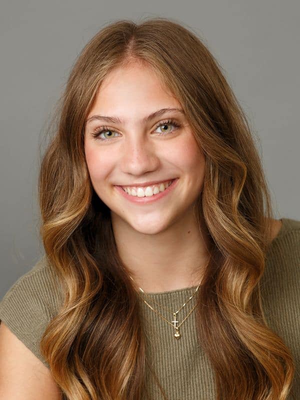 Smile transformation results Girl smiling after dental transformation with brown hair and green shirt