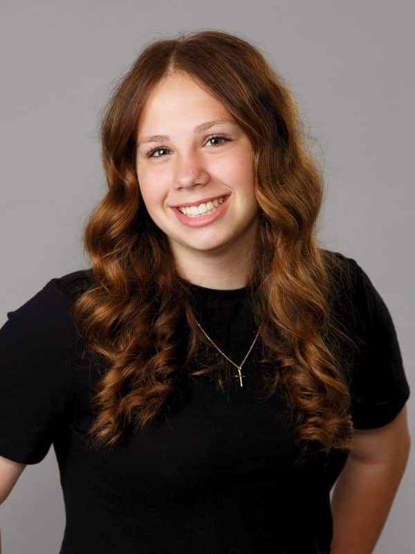 Confident smile after treatment Girl with brown curly hair smiling in black shirt after smile transformation