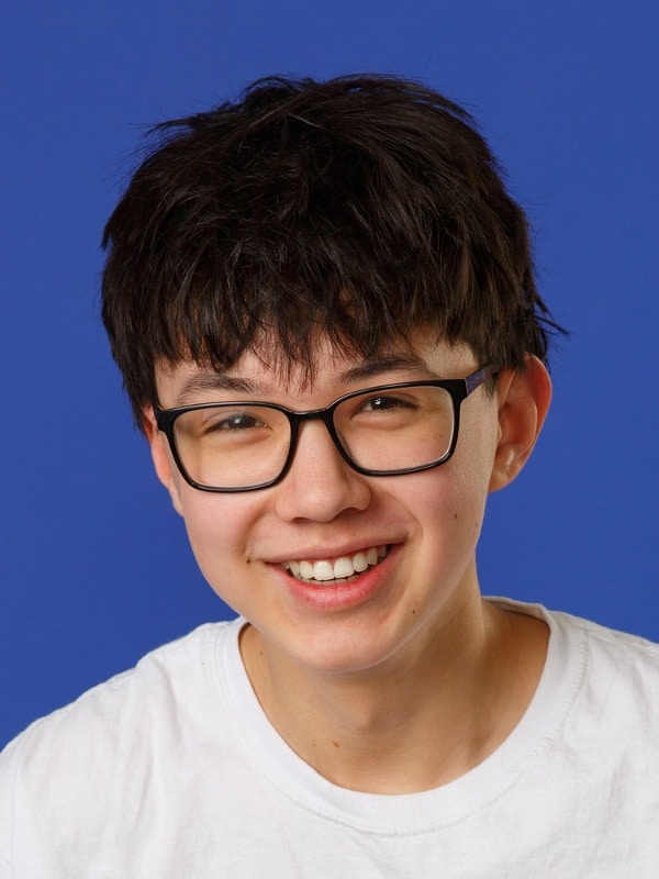 Jones-family-orthodontics-logan Young boy with black hair and glasses smiling in white shirt at jones family orthodontics